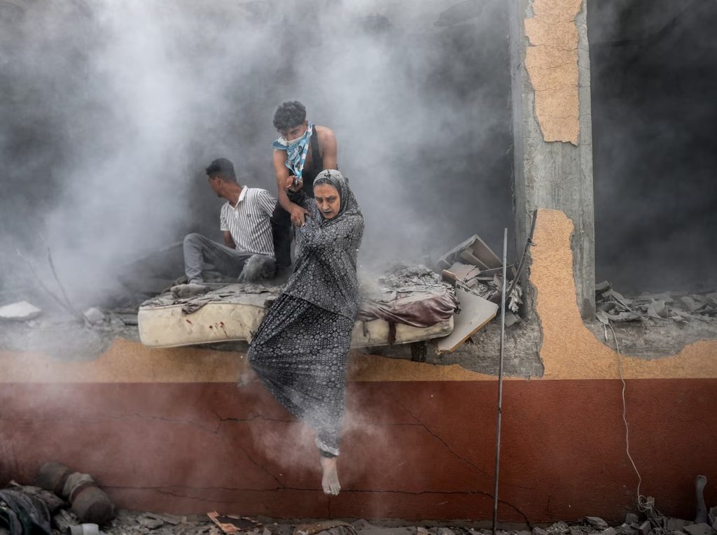 ایک فلسطینی خاتون اسرائیلی بمباری کا ہدف بننے والی عمارت سے نکل رہی ہے، تصویر: گارڈئین